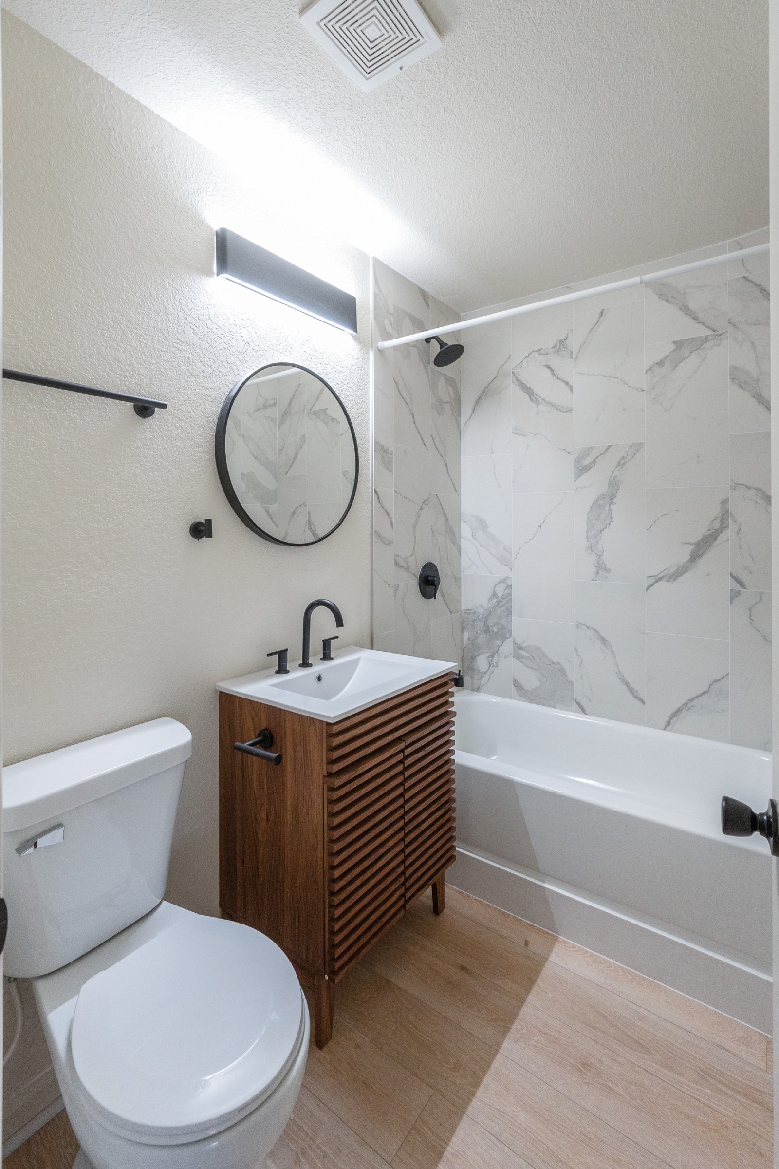 Full bathroom with marble tile and wood vanity